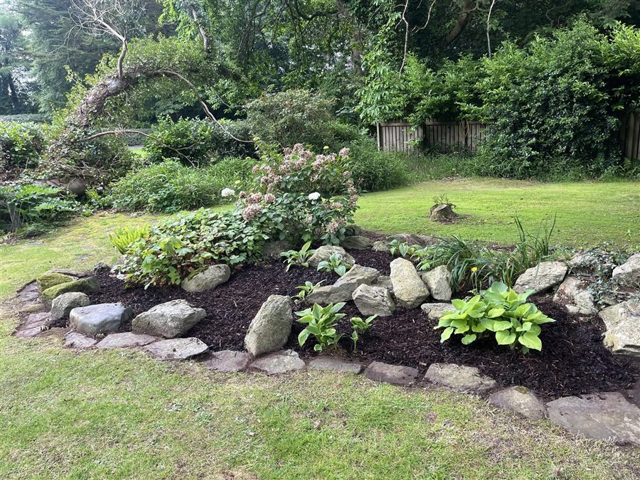 Landscaped rockery border with stone edging and hostas